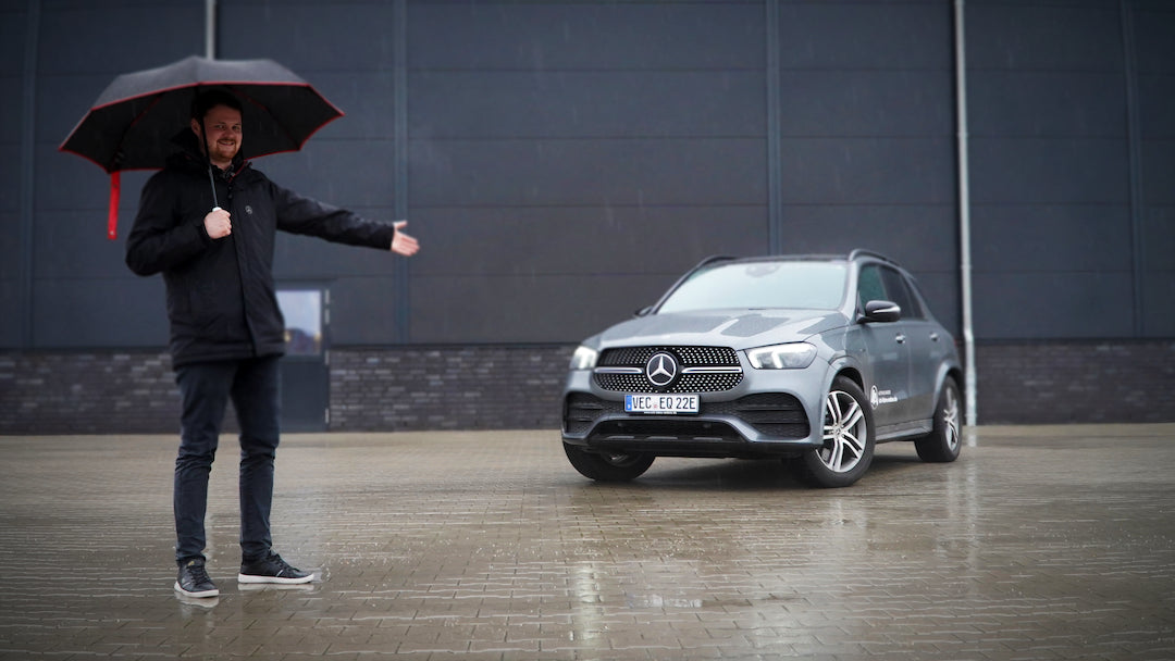 Mercedes-Benz im Regen mit Mann im Regenschirm